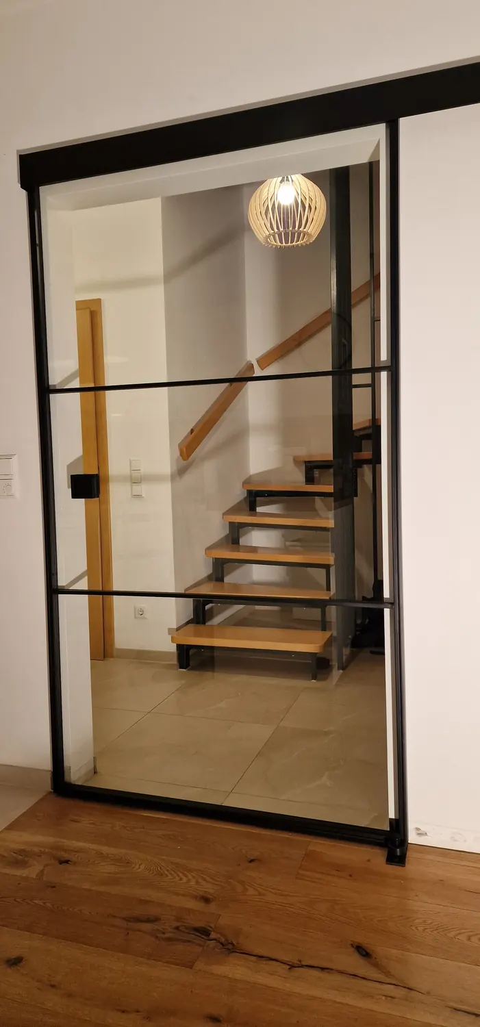 Schiebetür aus Stahl und Glas vor dem Treppenaufgang